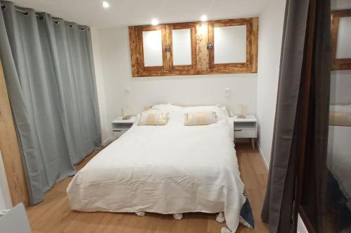 a bedroom with a white bed and two windows at La maison verte in Arreau