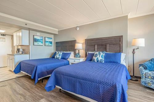 Dos camas en una habitación con edredones azules. en Great 1st floor unit that looks right out onto the beach with direct access, en Myrtle Beach