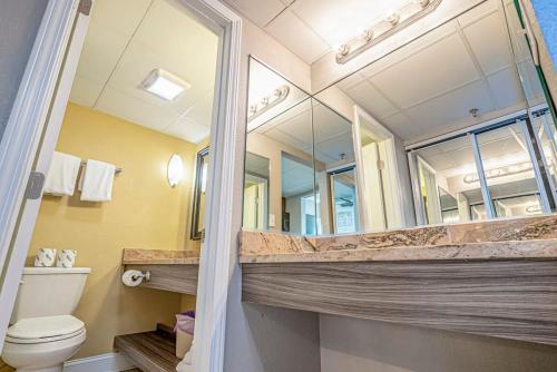 Un baño con inodoro y un espejo grande. en Great 1st floor unit that looks right out onto the beach with direct access, en Myrtle Beach