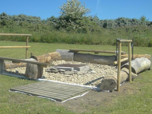 a fire pit with a bench and a picnic table at Hotel Aux Tamaris in Sauzon
