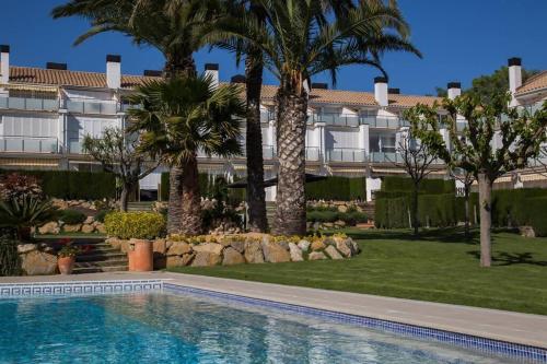 una piscina frente a un edificio con palmeras en Casa 8 Parc Sant Ramon descanso y armonía, en S'Agaró