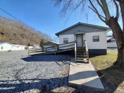 um pequeno edifício branco com uma escada ao lado de uma árvore em Spacious ATV Retreat House em Rock