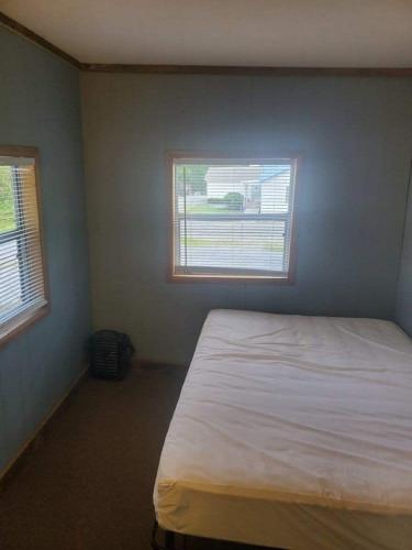 a bedroom with a white bed and two windows at Spacious ATV Retreat House in Rock