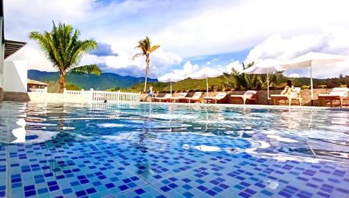 una gran piscina con azulejos azules en un complejo en Hotel Jardín Del Río, en El Bosque