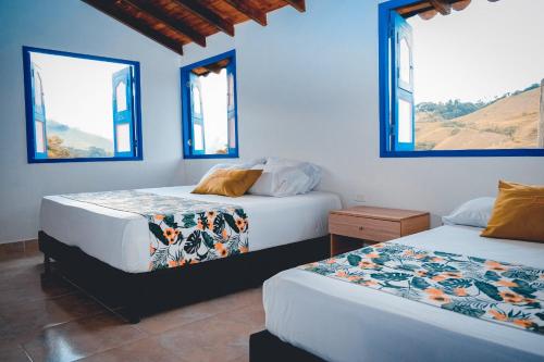 2 camas en una habitación con paredes y ventanas azules en Hotel Jardín Del Río, en El Bosque
