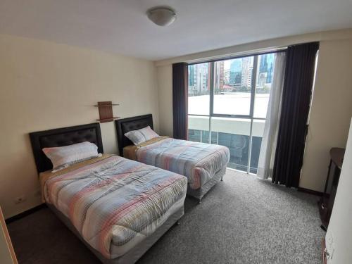 Cette chambre comprend deux lits et une grande fenêtre. dans l'établissement Beautiful apartment in Calacoto, à La Paz