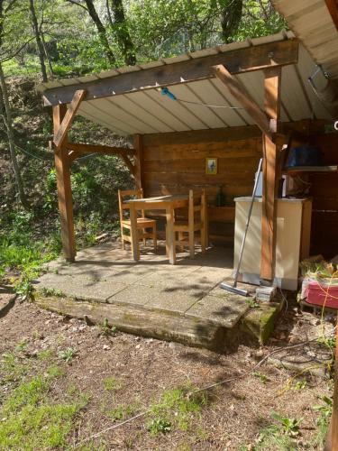 a wooden pergola with a table and chairs on a patio at Camping Les Escargots Bleus in Prades