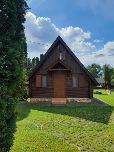a large wooden house with a grass yard at Őzike Apartmanházak in Bogács