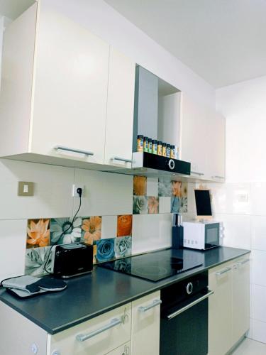 a kitchen with white cabinets and a black counter top at Hostel Central Skopje in Skopje