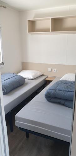 - 2 lits avec des oreillers bleus dans une chambre dans l'établissement MH 472 TOUT CONFORT de 36M2 3 chambres 1 salle de bain idéalement situé dans camping 4 étoiles, à Saint-Julien-en-Born