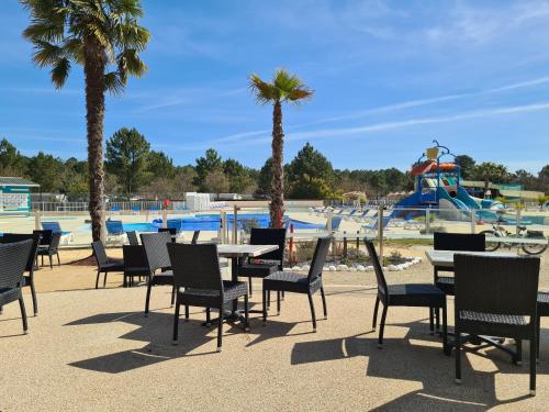 - une table et des chaises en face d'un parc aquatique dans l'établissement MH 472 TOUT CONFORT de 36M2 3 chambres 1 salle de bain idéalement situé dans camping 4 étoiles, à Saint-Julien-en-Born