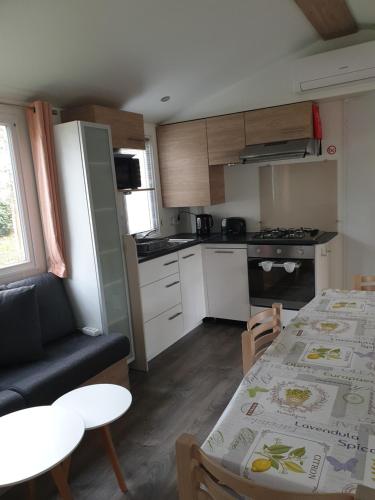 une petite cuisine avec une table et une salle à manger dans l'établissement MH 472 TOUT CONFORT de 36M2 3 chambres 1 salle de bain idéalement situé dans camping 4 étoiles, à Saint-Julien-en-Born