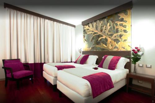 ミラノにあるラマダ プラザ ミラノのベッド2台が備わる客室で、壁には絵画が飾られています。