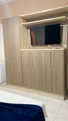 a bedroom with wooden cabinets with a flat screen tv at Pousada Castelo in Rio Branco