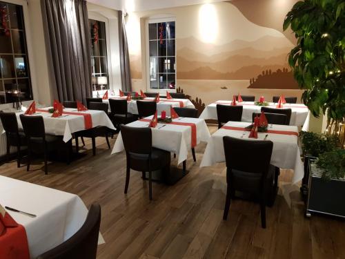 uma sala de jantar com mesas brancas e cadeiras pretas em Vittoria Hotel-Restaurant em Beverstedt