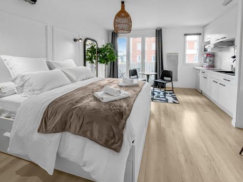 - une chambre blanche avec un grand lit et une cuisine dans l'établissement Balnéo-Ciné-Centre Historique à Troyes, à Troyes