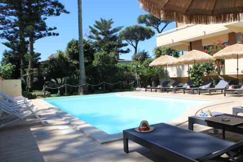 een zwembad met stoelen en parasols naast een resort bij Resort la Magnolia in Anzio
