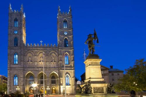 a statue in front of a building with a clock tower at M11 Bright Studio in the Heart of MTL in Montréal