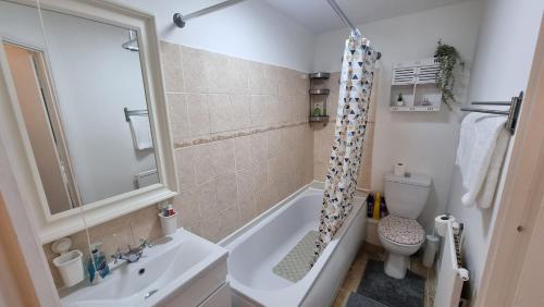 a bathroom with a tub and a toilet and a sink at Comfort at Enchanted Dwellings in London