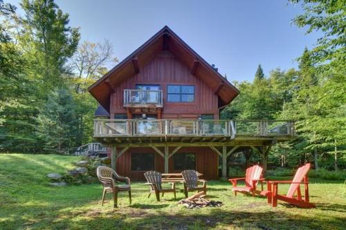 a large wooden house with a deck and chairs at Spacious log cottage Resort access in Lac-Superieur