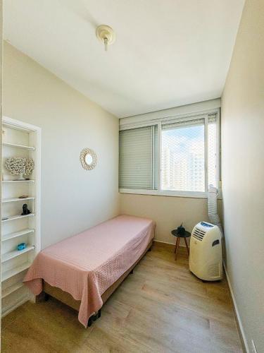 a small bedroom with a bed and a window at Apto vista mar em Pitangueiras, Guarujá in Guarujá