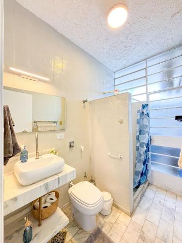 a bathroom with a sink and a toilet and a shower at Apto vista mar em Pitangueiras, Guarujá in Guarujá
