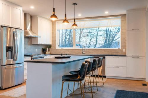 a kitchen with white cabinets and a island with bar stools at Le Zen Belvédère in Sainte-Adèle