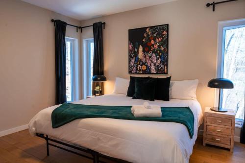 a bedroom with a large bed with a painting on the wall at Le Zen Belvédère in Sainte-Adèle