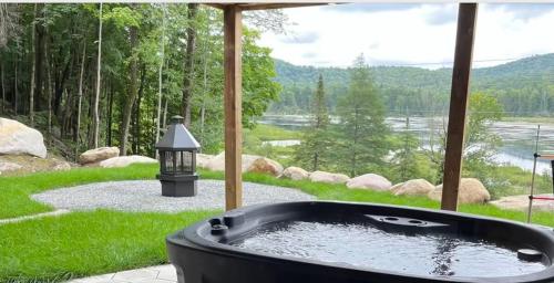 a hot tub in a yard with a view of a lake at Lakeview Mid Century Luxury Cottage in Sainte-Adèle