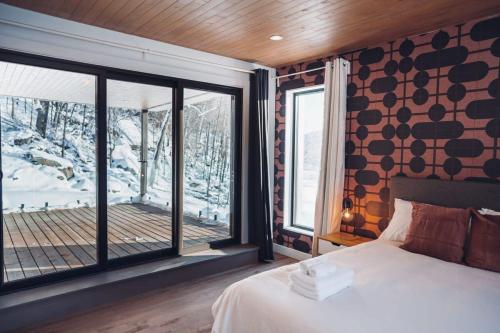 um quarto com uma cama e uma grande janela em Lakeview Mid Century Luxury Cottage em Sainte-Adèle