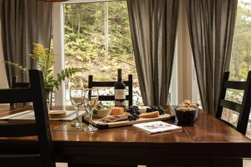 a dining room table with a bottle of wine and glasses at Le Mésangeai in Lac-Superieur