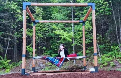 a woman is sitting on a swing at Le Mésangeai in Lac-Superieur