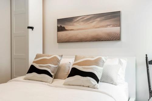 蒙特朗布朗的住宿－Le P'tit Caché 4 min de Ski Tremblant，卧室配有一张白色床,墙上挂有绘画作品