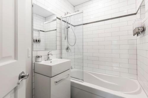a white bathroom with a sink and a shower at Le P'tit Caché 4 min de Ski Tremblant in Mont-Tremblant