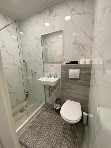 a bathroom with a toilet and a sink and a shower at Apartman Kiara in Mostar