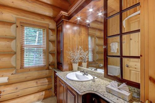 een badkamer in een blokhut met een wastafel en een spiegel bij Waterfront - Perfect Family fun in Mille-Isles