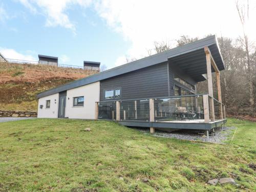 a large house with a large deck on a yard at Coorie In in Aberfeldy