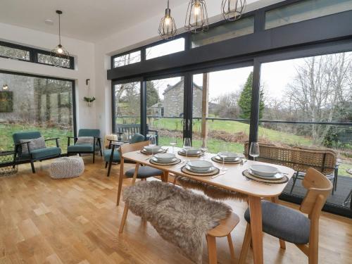 a dining room with a table and chairs and large windows at Coorie In in Aberfeldy
