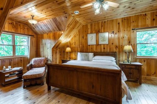 1 dormitorio con 1 cama, 1 silla y paredes de madera en CA Rhuddin, en Labelle