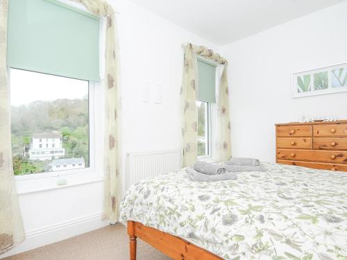 a bedroom with a bed and a large window at Lowena Cottage in Looe