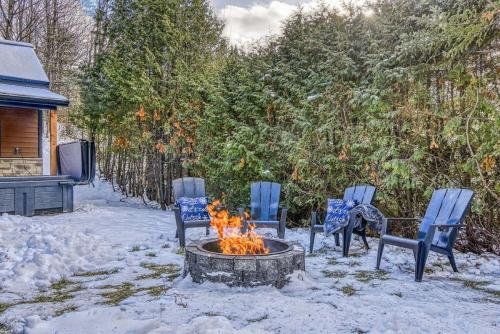 four chairs and a fire pit in the snow at Le mini chalet in Sainte Anne des Lacs