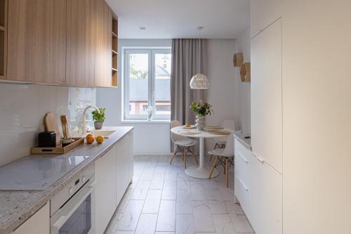 a kitchen with white cabinets and a table in it at Apartament Skandynawia in Ustroń