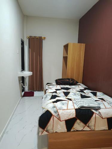 ein Schlafzimmer mit einem Bett mit einer Bettdecke darauf in der Unterkunft Losmen cempaka in Sibengkok
