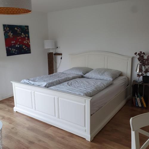 a white bed in a room with a white wall at Ferienwohnung an der Trave in Bad Segeberg