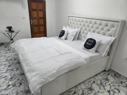 a large white bed with two pillows on it at Chambre Meublée à Douala, Bonapriso - Armée del'air in Douala