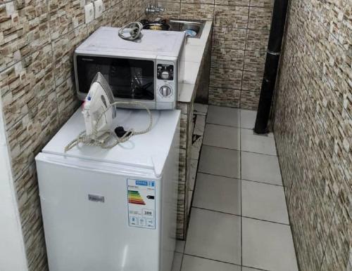 Un four micro-ondes est installé au-dessus d'un réfrigérateur. dans l'établissement Chambre Meublée à Douala, Bonapriso - Armée del'air, à Douala