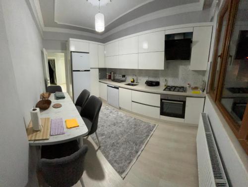 a kitchen with white cabinets and a table and chairs at Seafront Apartment Rize-Ardeşen in Ardeşen