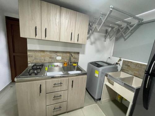 uma cozinha com armários de madeira, um lavatório e um frigorífico em Apartaloft en el centro 302 em Pereira