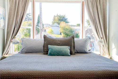 a bed with two pillows and a large window at #StayinMyDistrict Heritage House Private Suite in Coos Bay