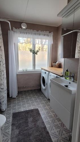a bathroom with a washing machine and a window at Mysig stuga i Svärtinge in Svärtinge